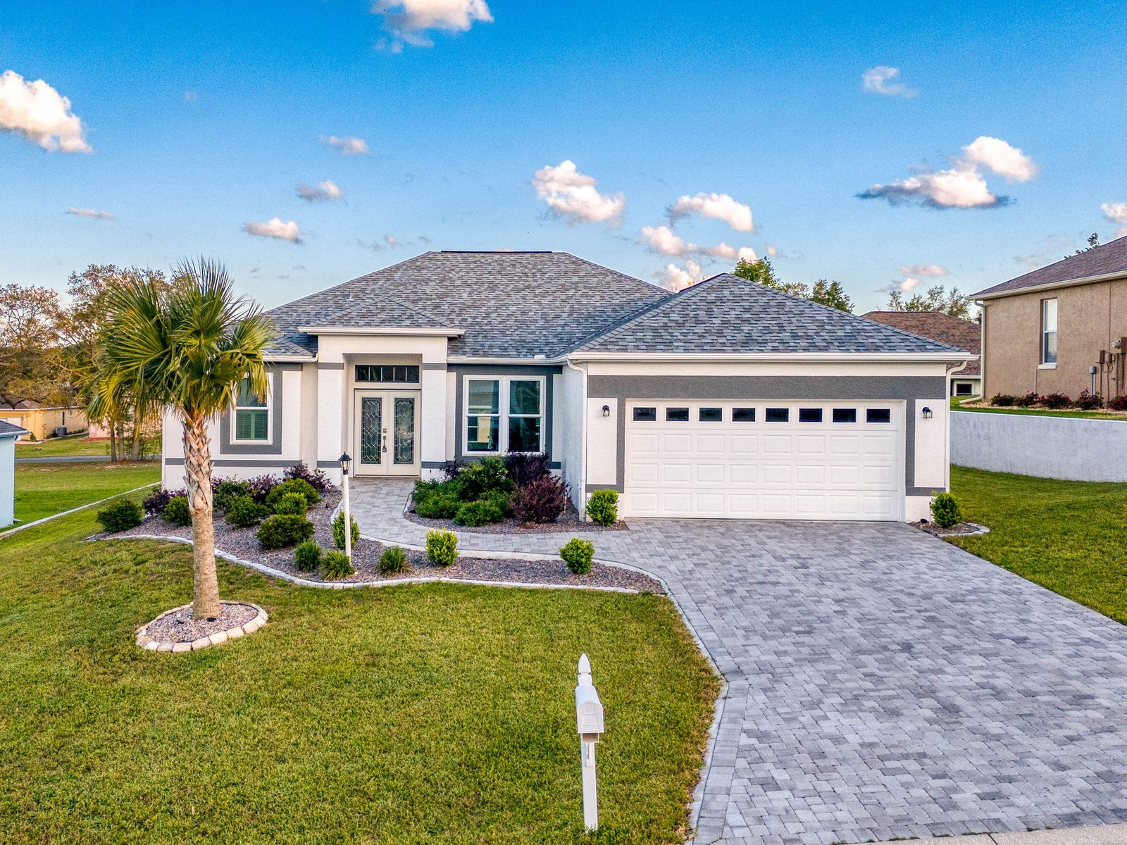 White single-story home at 224 W Rexford Dr with gray roof, paver driveway, and a two-car garage