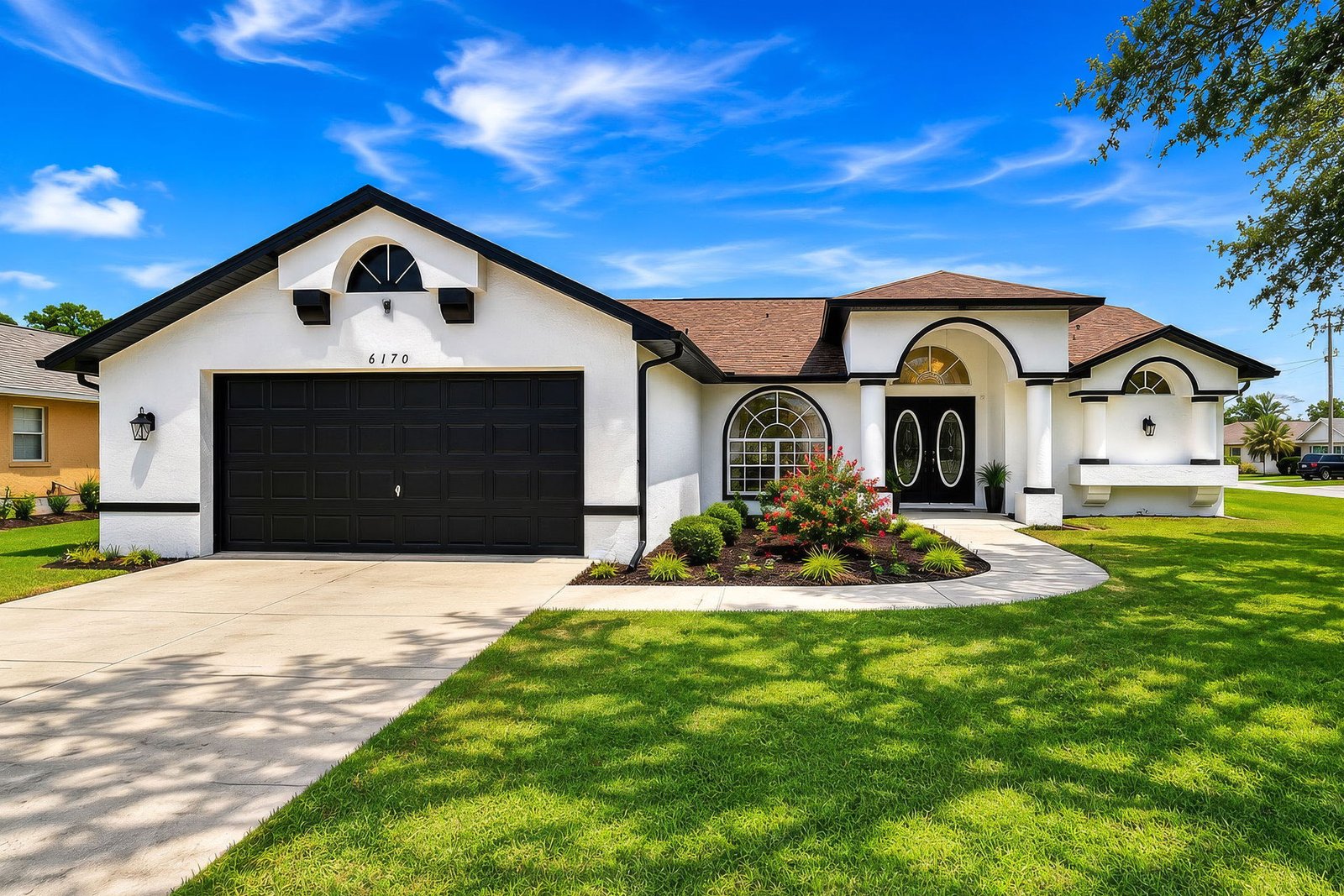 White single-story home at 6170 Gainsboro Ave with black trim, arched front entry, and a two-car garage